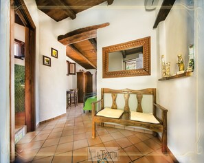 A hallway with a wooden bench, a mirror, and a shelf with decorative items. - B&B La Torretta (Maratea)