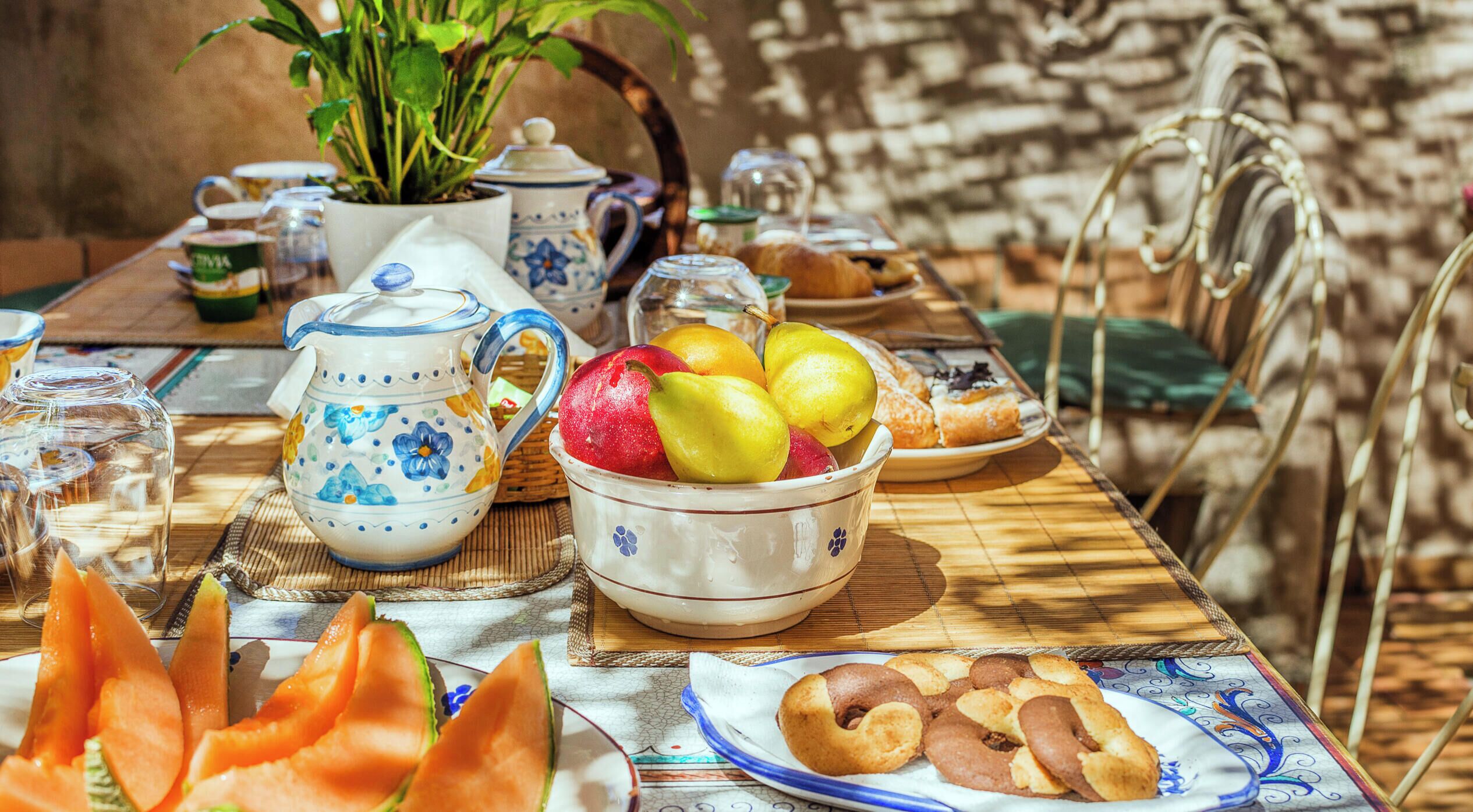 A table set with a variety of food items, including fruits, pastries, and a pitcher.