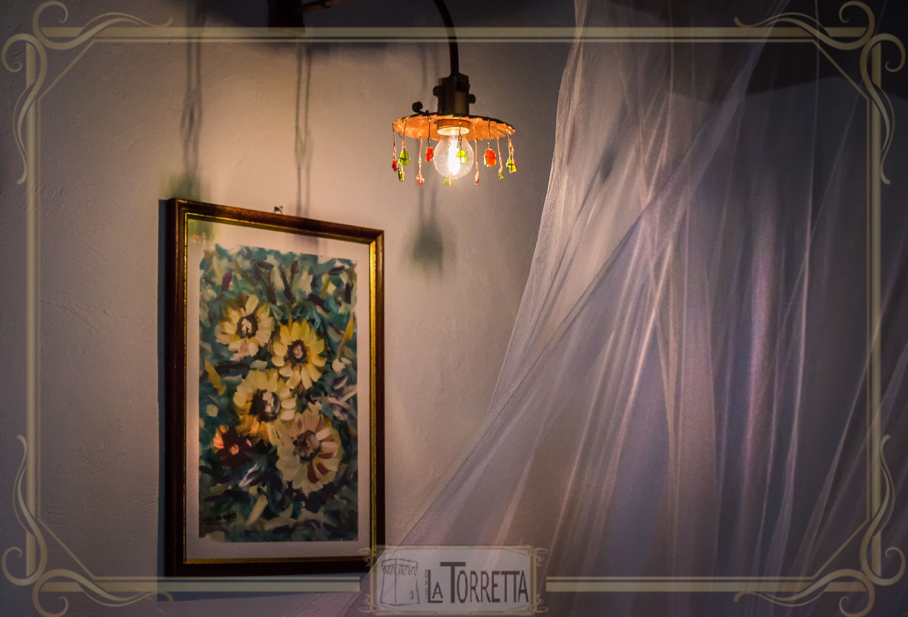 A framed painting of flowers, a hanging light fixture, and a sign reading "La Torretta".