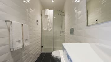 A modern bathroom with a glass-enclosed shower, a white toilet, and two towels hanging on a rack.