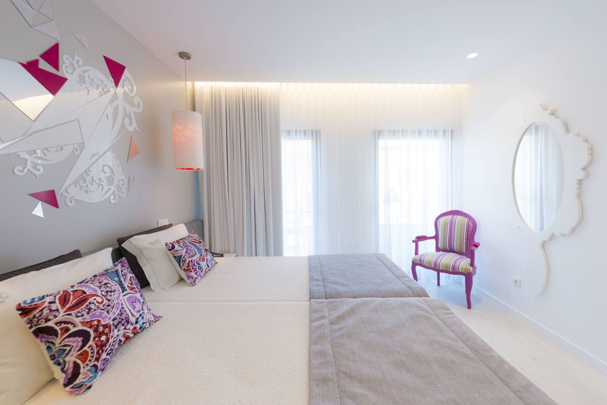 A modern bedroom with a large bed, a chair, and a decorative wall.