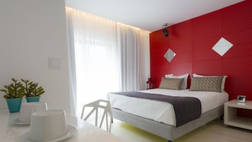 Habitació d'hotel moderna amb llit, taula de nit i finestra amb cortines.