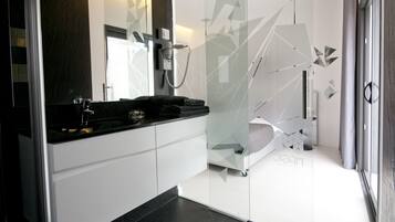 A modern bathroom with a glass shower enclosure, a black countertop, and a white vanity.