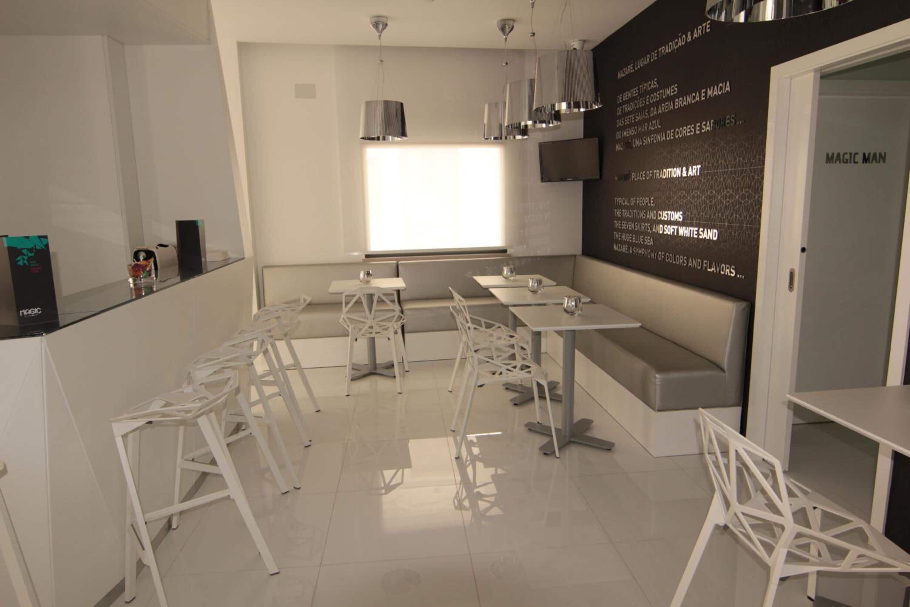 Un restaurante moderno con mobiliario blanco, un ventanal grande y una pizarra con el menú.
