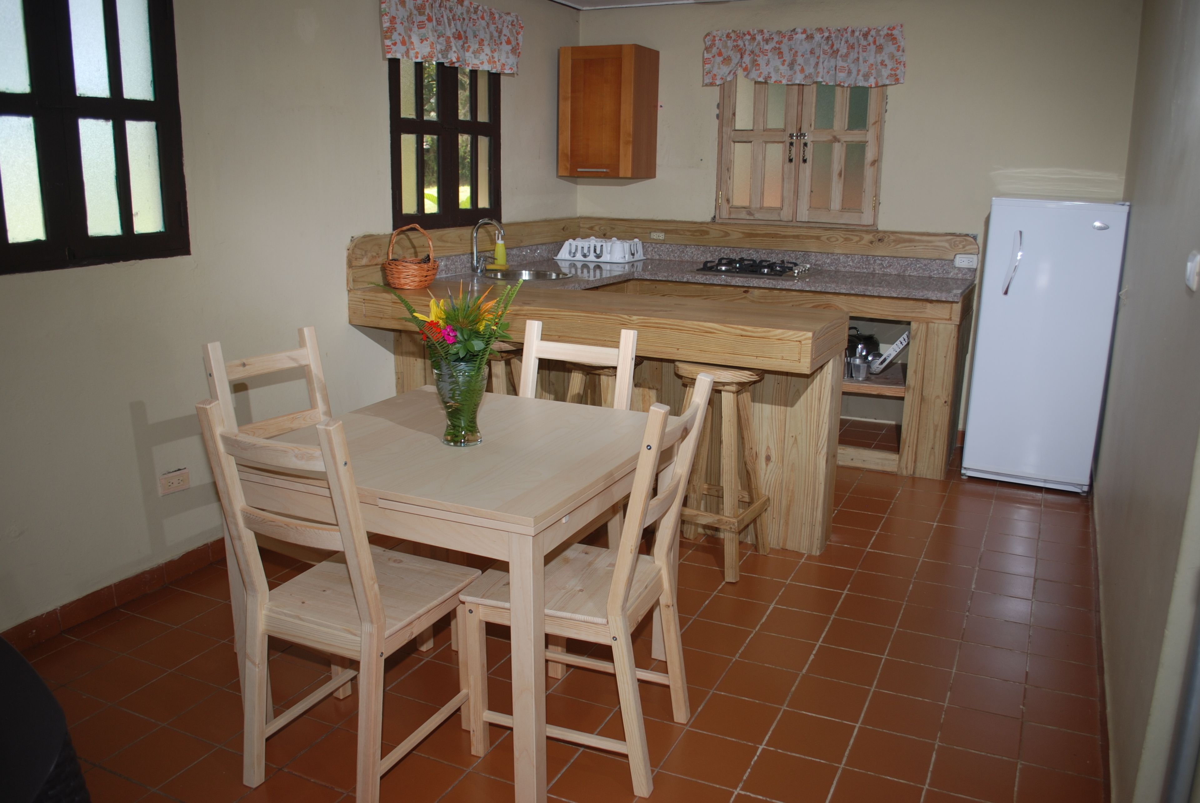 Una cocina con armarios de madera, un refrigerador blanco y una mesa de comedor con sillas.