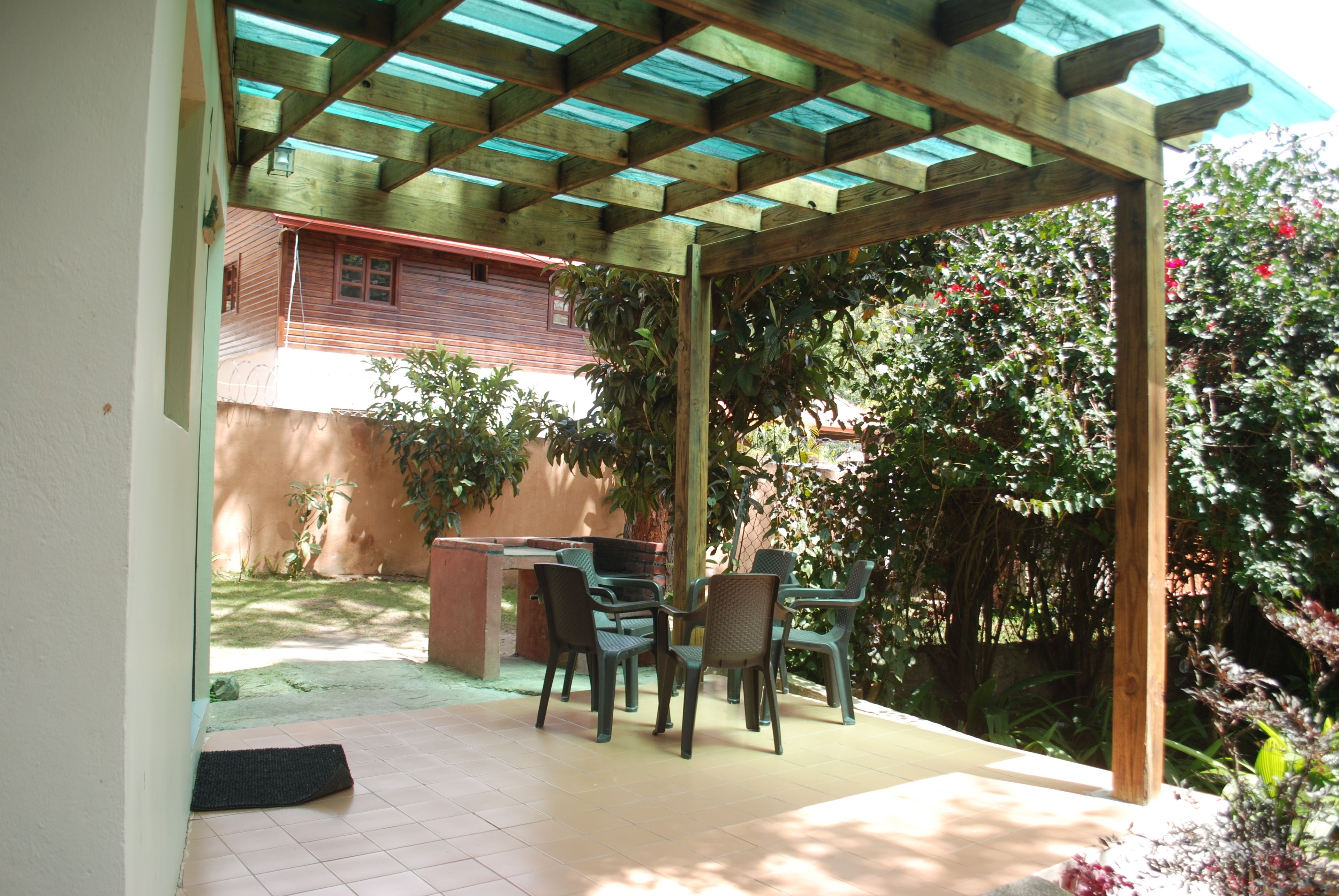 An outdoor patio with a wooden pergola, a table, and chairs.