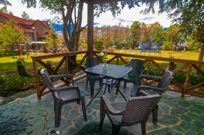 An outdoor patio with a table and chairs, surrounded by a wooden fence and greenery.