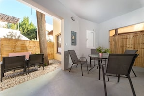 Un patio al aire libre con una mesa, sillas, una cerca de madera y un árbol.