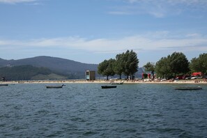 Una playa con barcos, una torre de salvavidas y árboles.