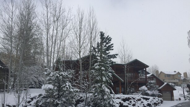 A snow-covered landscape with a wooden cabin and a stone wall. - Jeremy House (Park City)