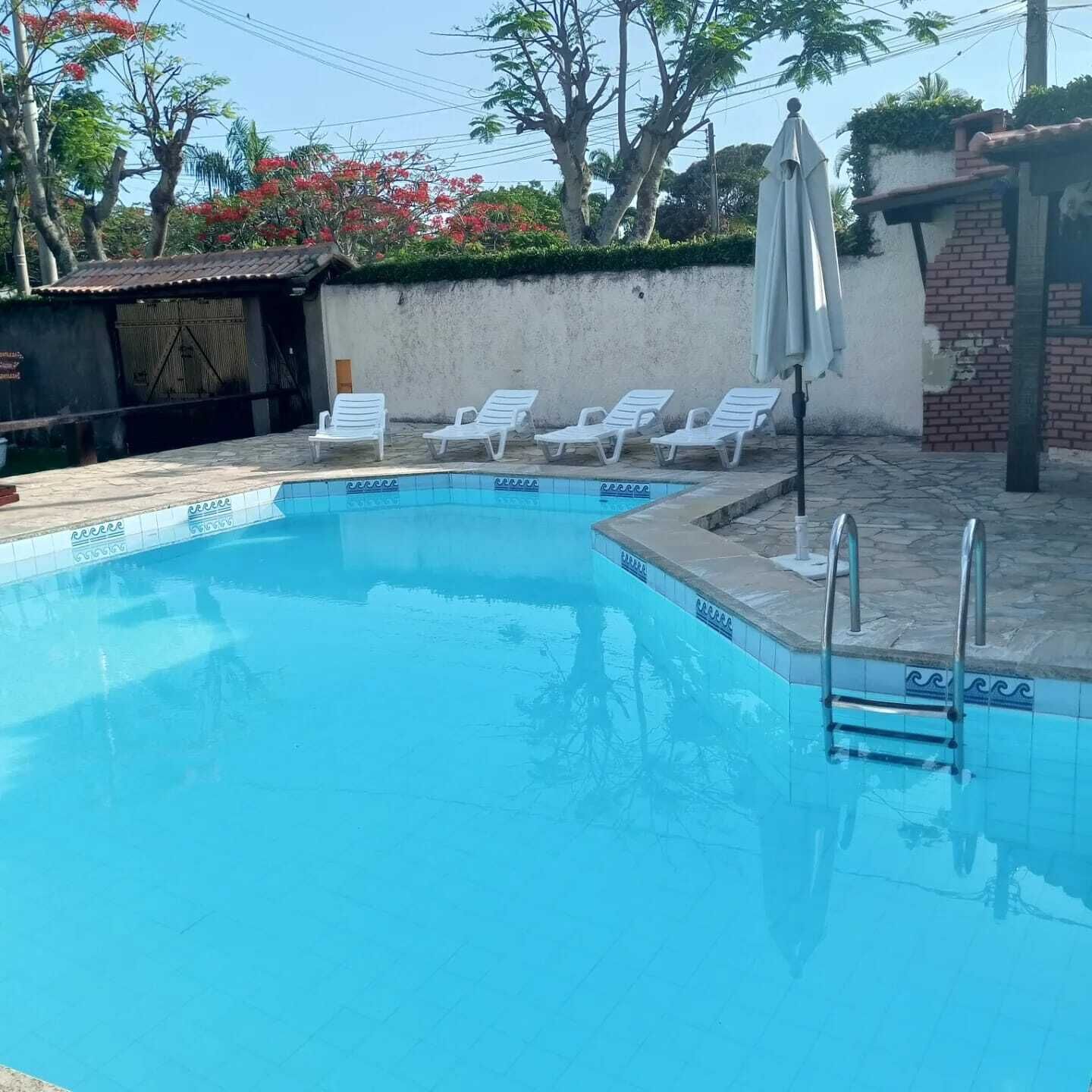 Una piscina con sillas de descanso blancas y una escalera.
