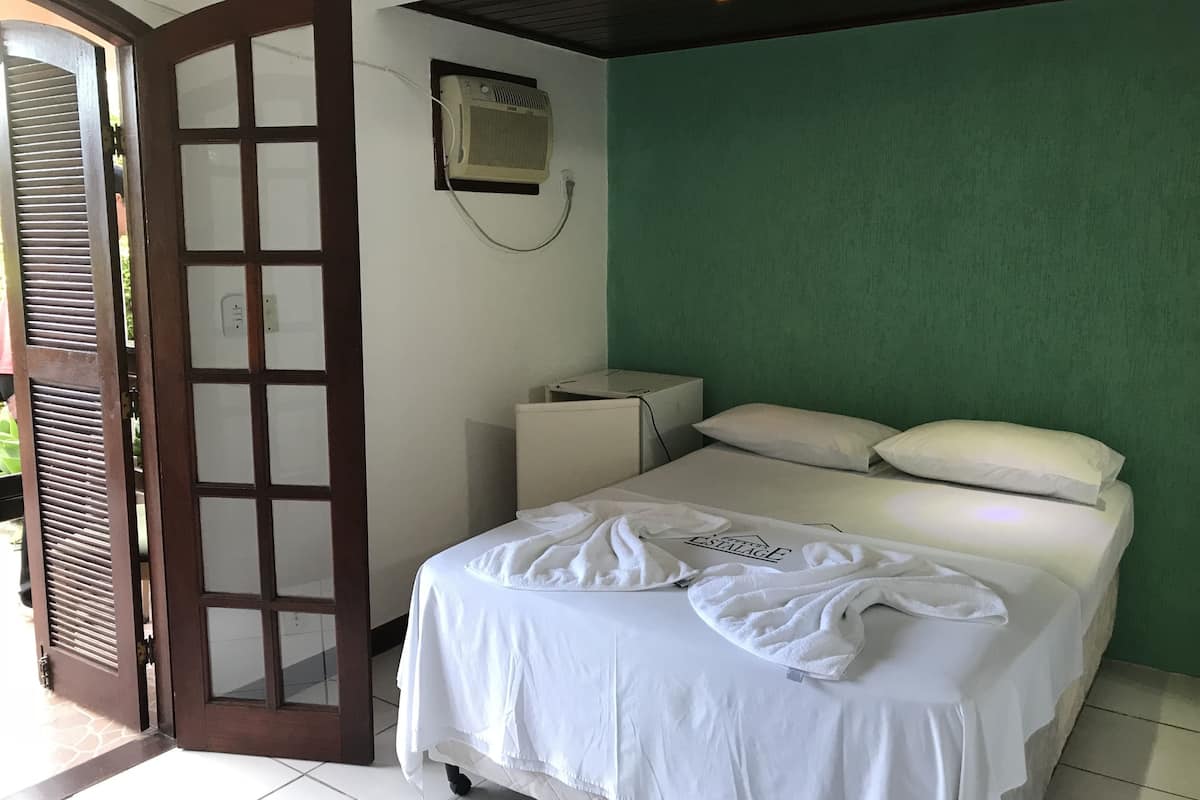 Ein Schlafzimmer mit einem Bett, einer weißen Wand, einer grünen Wand, einem Fenster und einer Tür.