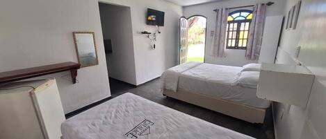 A hotel room with two beds, a small refrigerator, a mirror, and a ceiling fan.