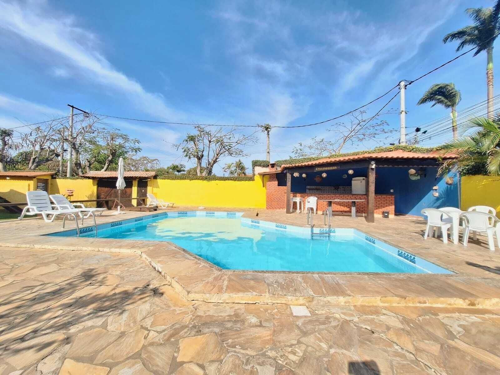 A swimming pool with lounge chairs, a small bar area, and a yellow wall.