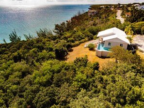 A white villa with a pool, surrounded by dense greenery and overlooking a beach. - Beautiful home in TOP location - PRIVATE HEATED POOL-Last minute XMAS deal! (Governor's Harbour)