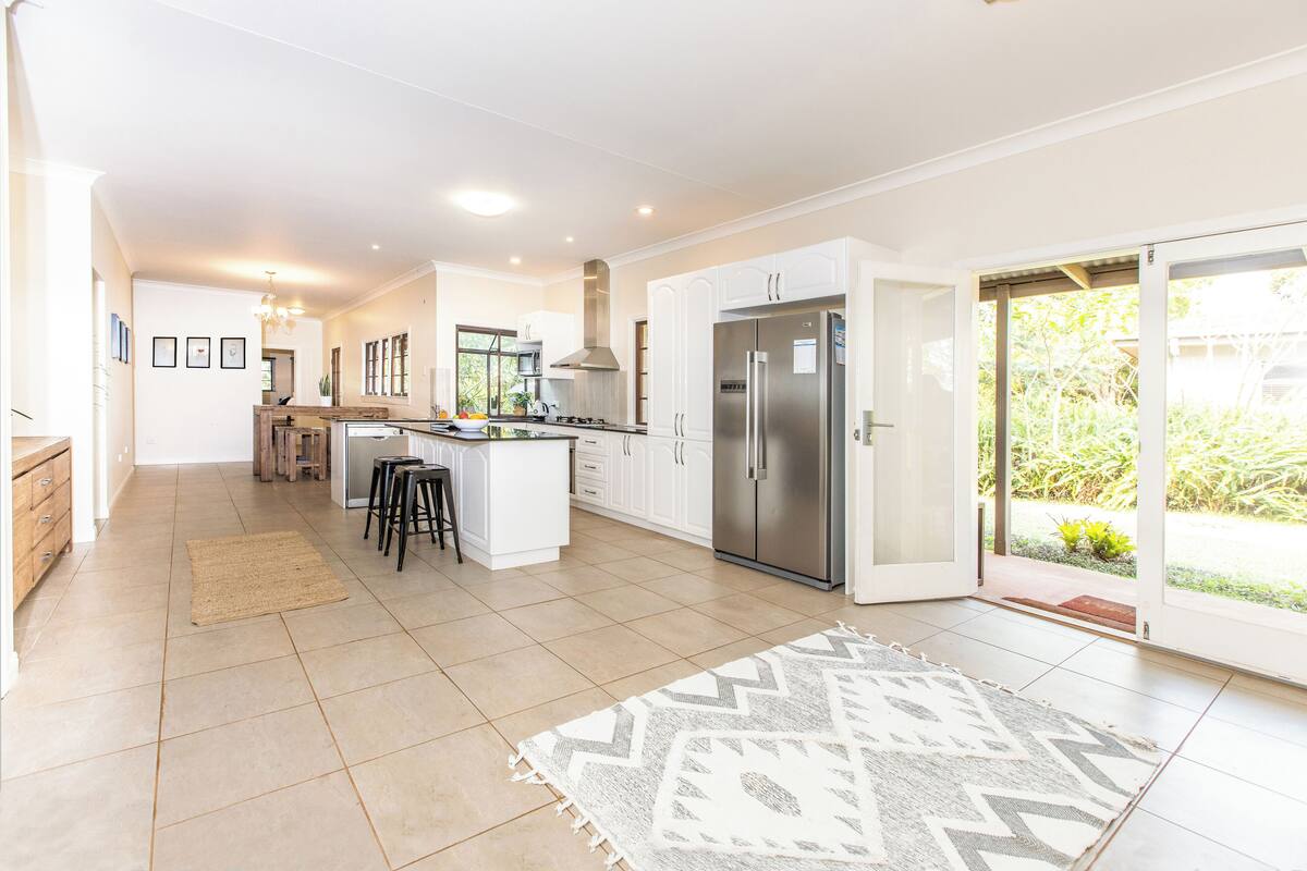 A modern kitchen with white cabinets, a stainless steel refrigerator, and a central island with stools.