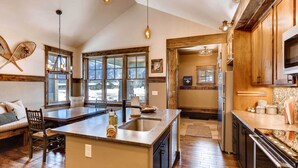 Una cocina amplia con una isla grande, muebles de madera y vistas al exterior a través de ventanas grandes.