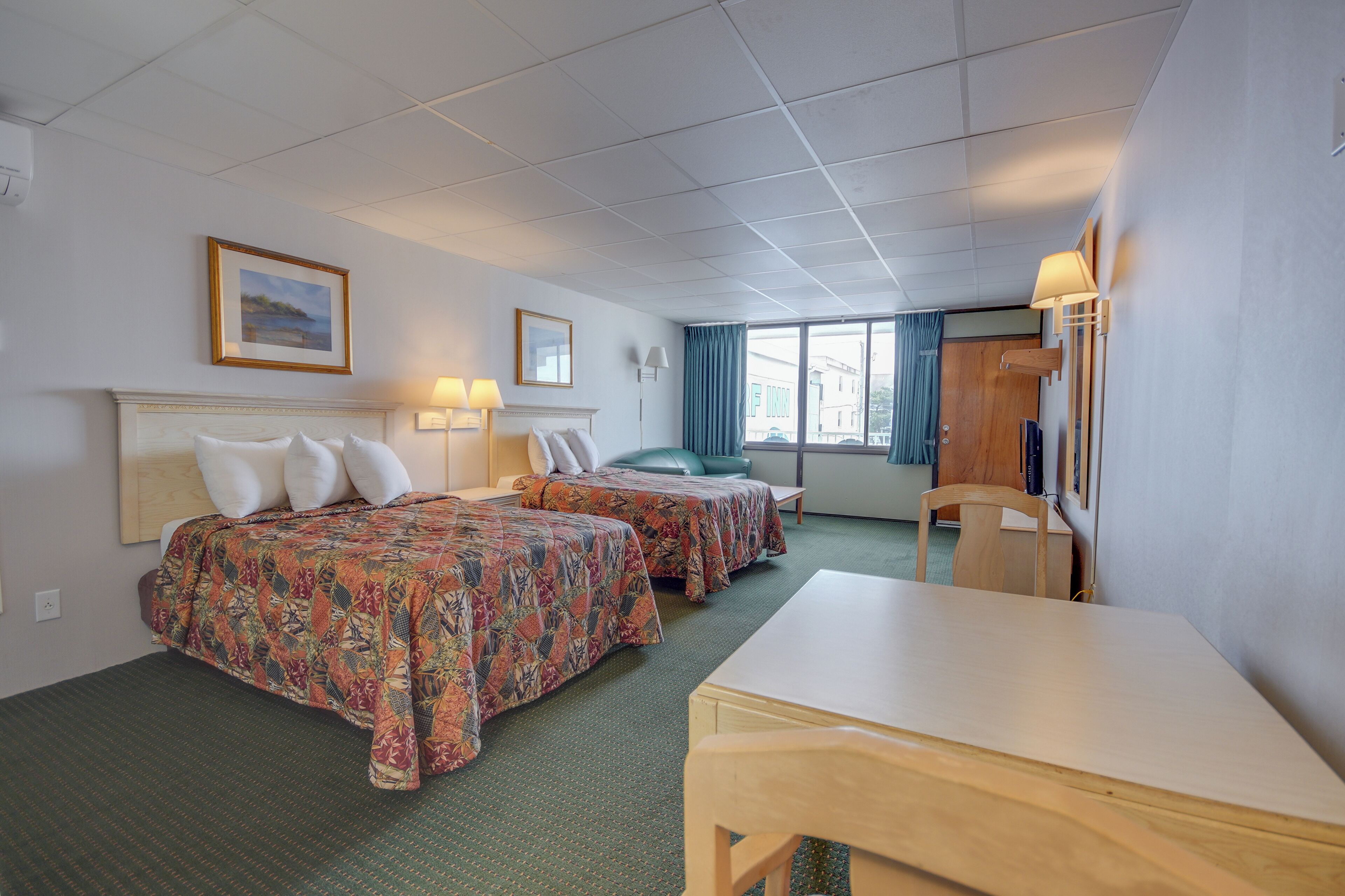 Une chambre d’hôtel avec deux lits, un bureau et une chaise.