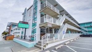 A building with a sign indicating 'SURF INN and Suites' and a 'VACANCY' sign. It has a white exterior with balconies and a parking lot in front. - Surf Inn Suites (Ocean City)