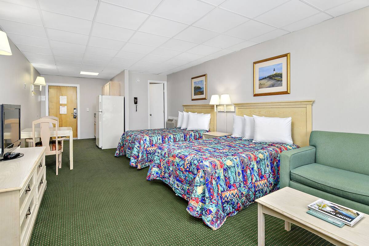 A hotel room with a bed, a sofa, a desk, and a television.