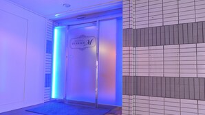 A hotel entrance with a frosted glass door labeled "TERRACE M" and a blue-lit pathway leading to it. - TERRACE M YOKOTA BASE - Adults Only (Mizuho)