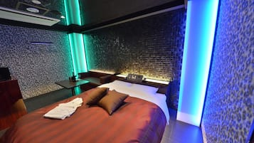A modern hotel room with a large bed, a nightstand, and a wall with a textured pattern.