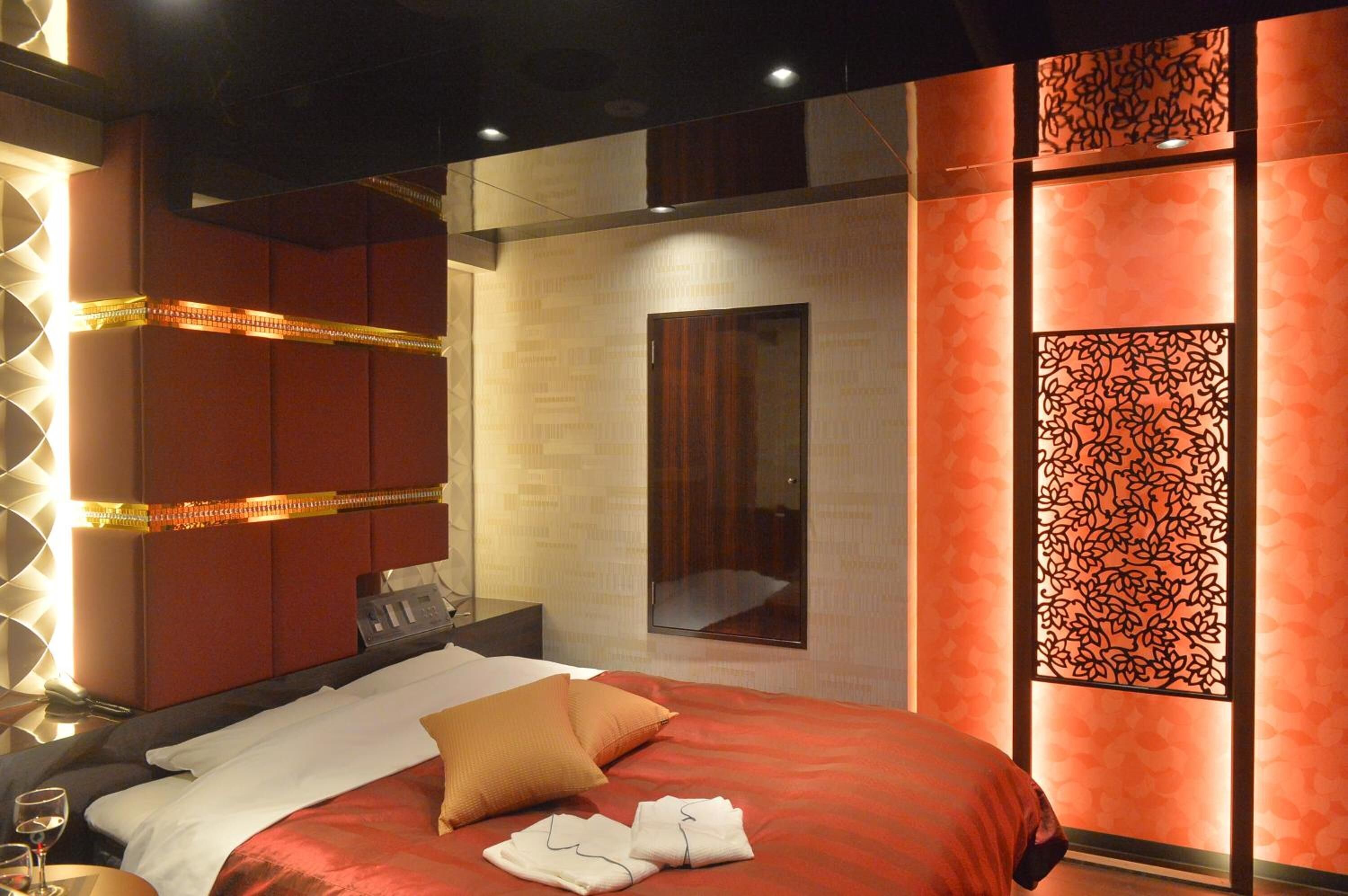 A modern hotel room with a large bed, a bedside table, and a mirror.
