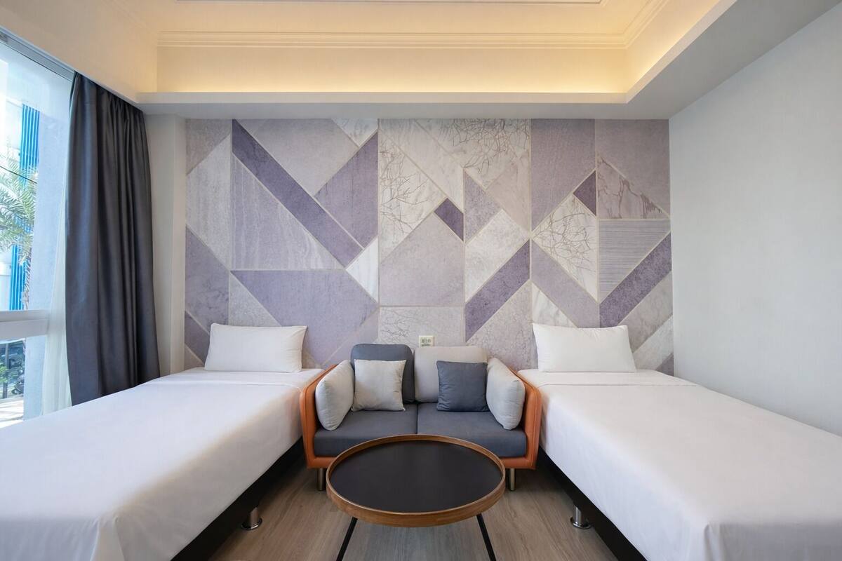 A hotel room with two beds, a sofa, and a round coffee table.