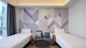 A hotel room with two beds, a sofa, and a round coffee table.