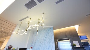 A modern interior with a marble wall, a reception desk, and a ceiling with a unique light fixture. - Blue Ocean BnB (Hualien City)