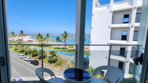 A balcony with a view of a beach, palm trees, and a road with cars. - Blue Ocean BnB (Hualien City)