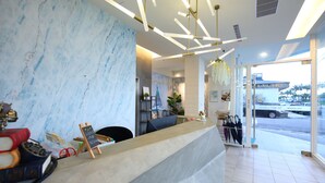 A reception area with a marble wall, a reception desk, and a view of the street outside. - Blue Ocean BnB (Hualien City)