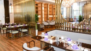 A restaurant with wooden floors, tables set with purple napkins, and a modern chandelier. - Shanshui S Hotel Maliandao (Beijing)