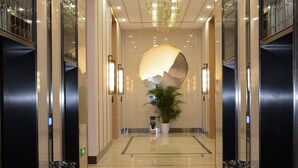 A modern hotel lobby with a central staircase, a large potted plant, and a decorative wall feature. - Shanshui S Hotel Maliandao (Beijing)