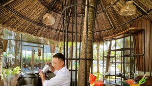 A restaurant with a thatched roof, a bar area, and a view of the outdoors.