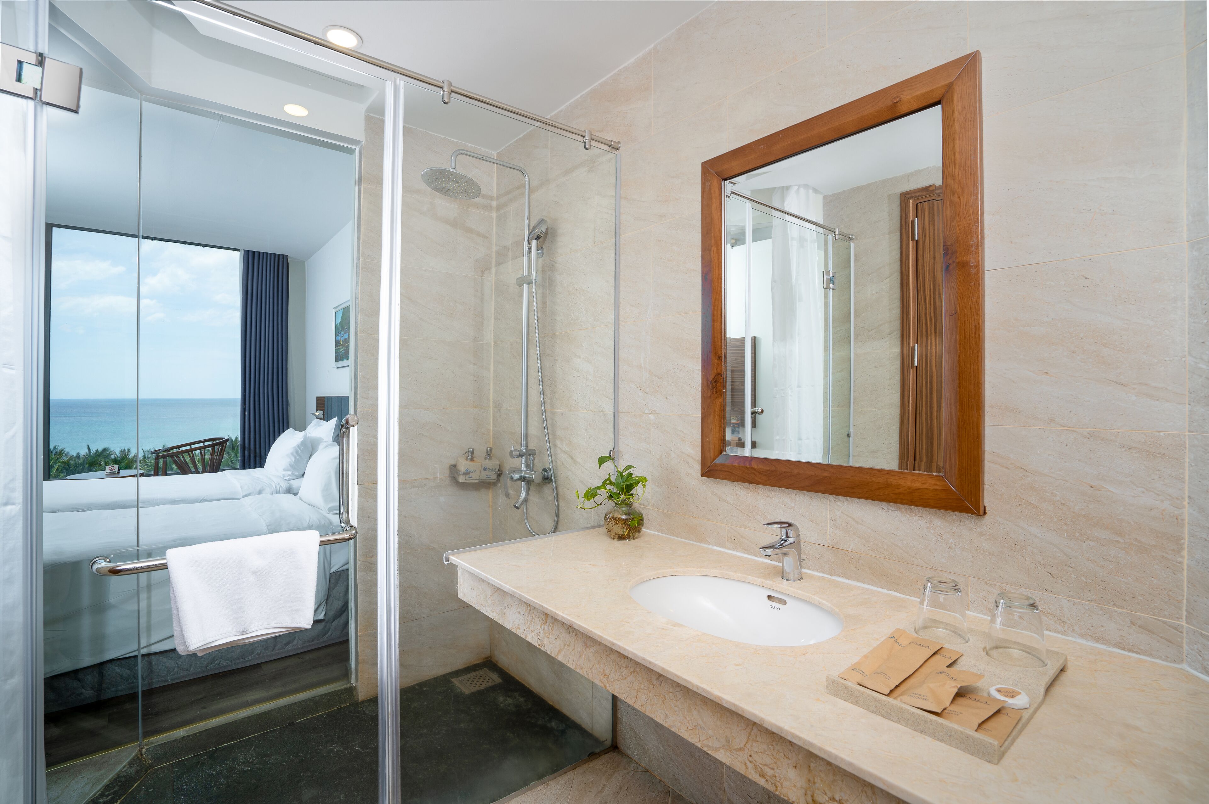 A modern bathroom with a glass-enclosed shower, a large mirror, and a marble countertop.
