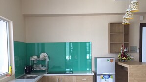 A modern kitchen with wooden cabinets, a stainless steel sink, and a refrigerator. - Hoang Ky Hotel (Bac Nha Trang)
