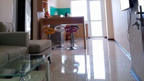 A modern living room with a glass coffee table, a sofa, and a ceiling fan. There are three pendant lights and a TV mounted on the wall. - Hoang Ky Hotel (Bac Nha Trang)