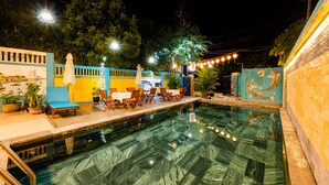 An outdoor swimming pool with a dining area and lounge chairs. -  B'Lan Riverside Villa (Da Nang)