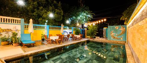 An outdoor swimming pool with a dining area and lounge chairs.