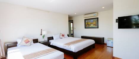 A hotel room with two beds, a television, and a painting on the wall.