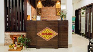 A reception desk with a 'PLAN' sign, a brick wall, wooden slats, and a reception area with a signboard. -  B'Lan Riverside Villa (Da Nang)