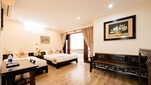 A hotel room with a wooden floor, two beds, a desk, a chair, a bench, a painting, and a window with curtains. -  B'Lan Riverside Villa (Da Nang)