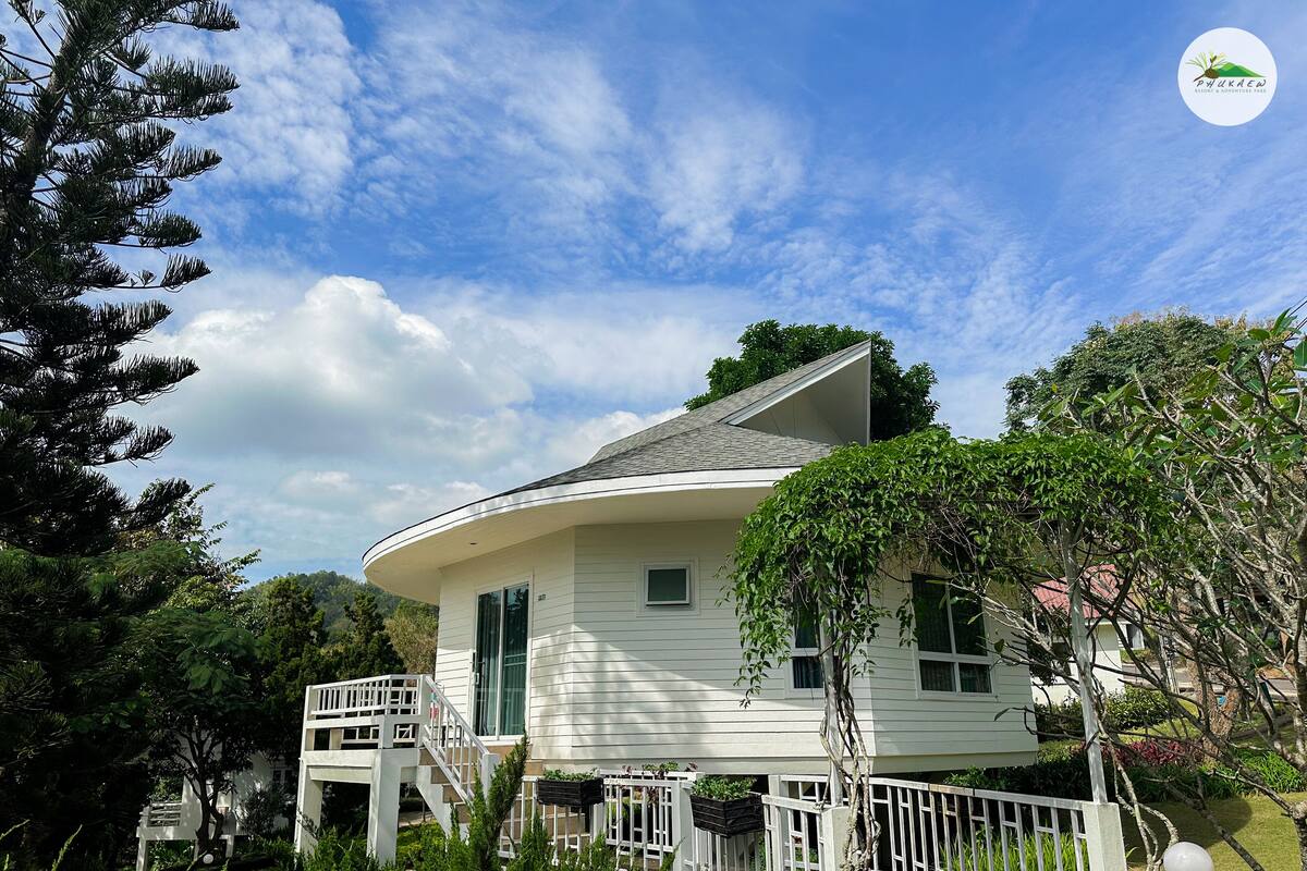 A white house with a curved roof, a white porch, and a staircase leading to the entrance.