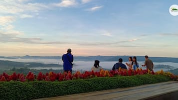 A group of people on a scenic overlook with a view of distant mountains and a misty valley.