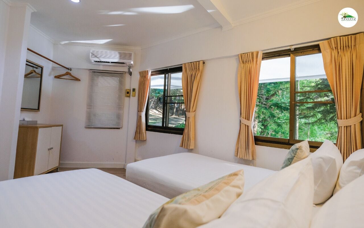Hotelkamer met twee bedden, een kledingkast, een airconditioning en een raam met gordijnen.