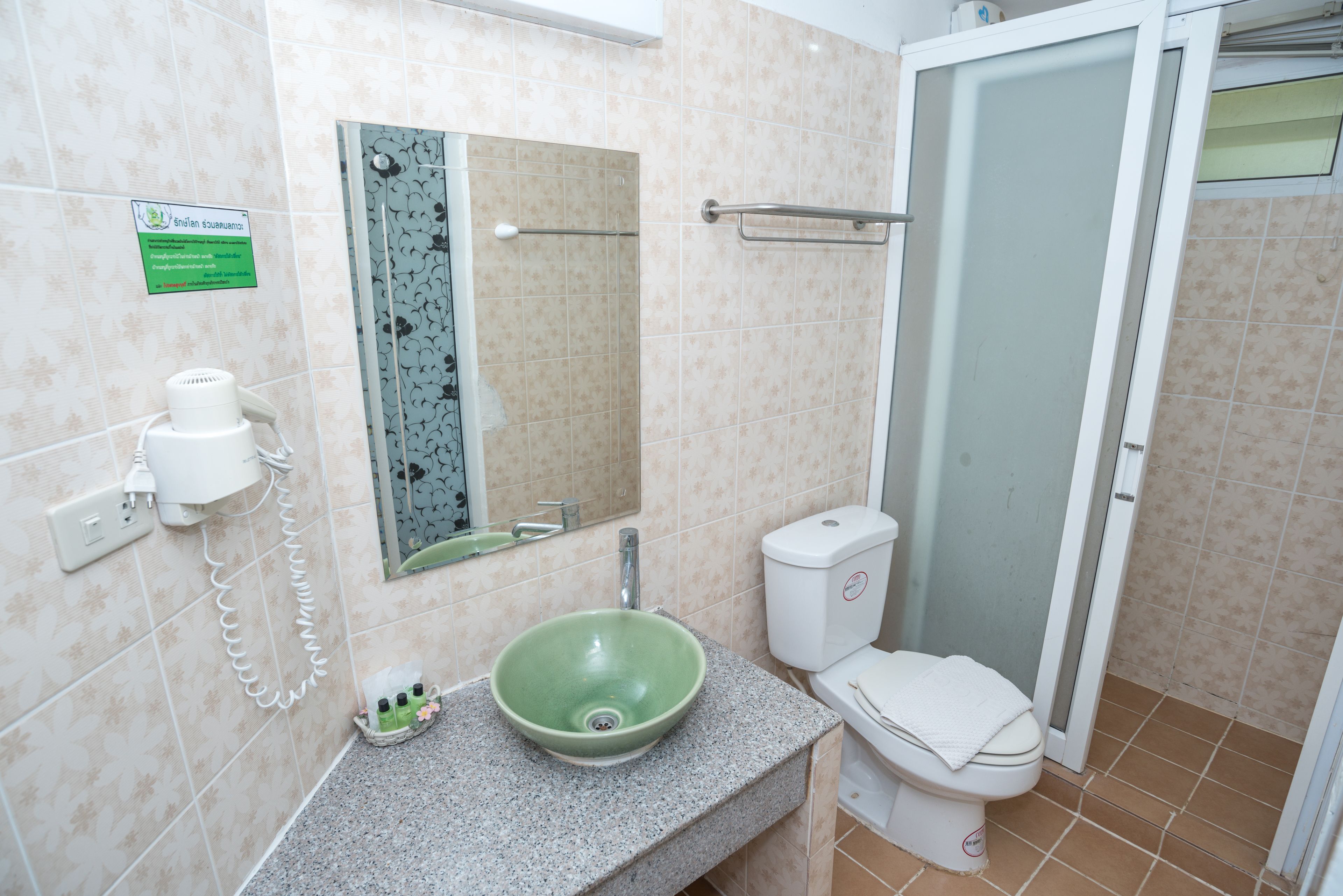 A bathroom with a green sink, a toilet, a shower with a glass door, and a towel rack.