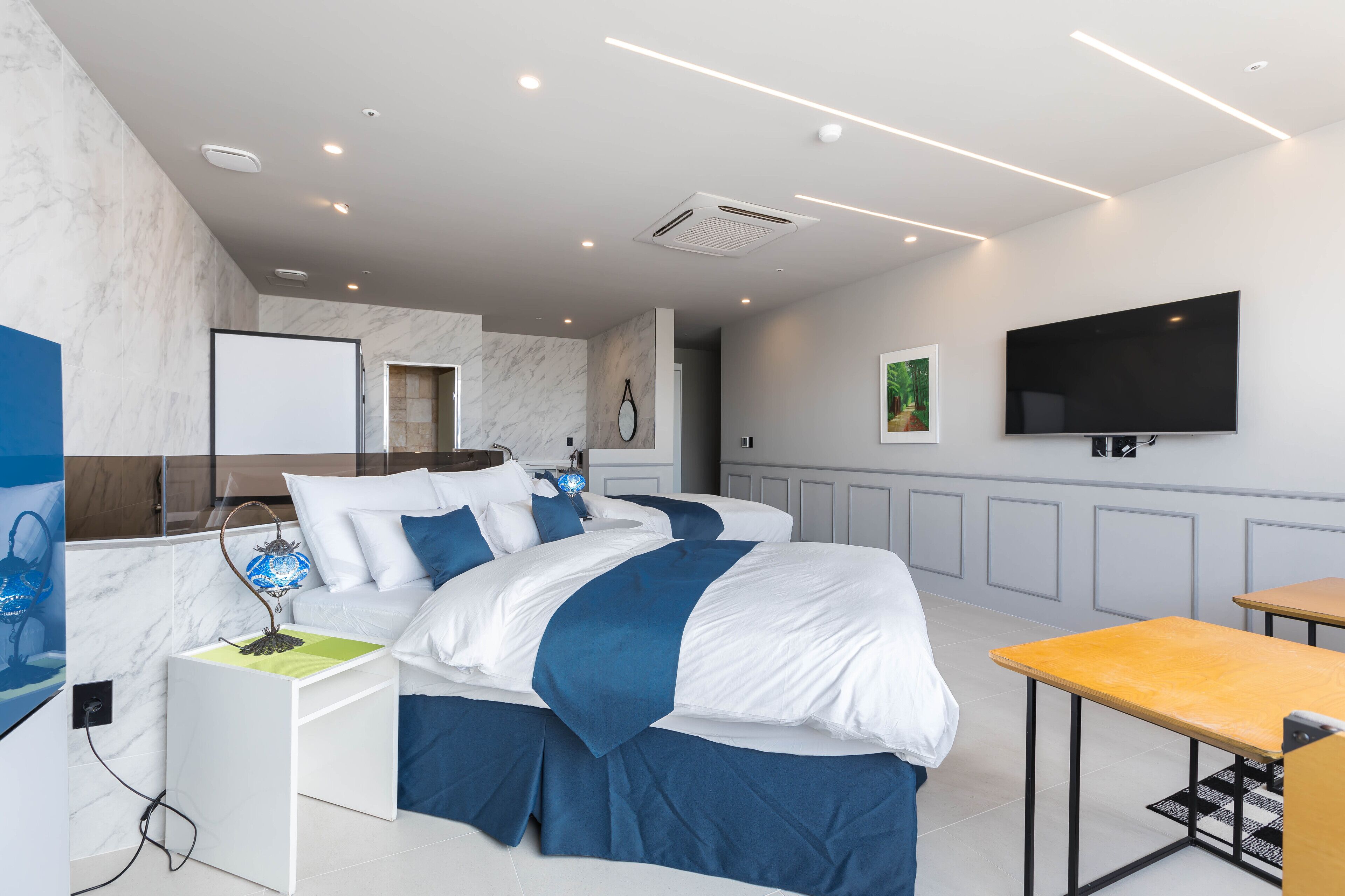 Una habitación de hotel moderna con una cama grande, un escritorio, un televisor de pantalla plana y un ventanal amplio.