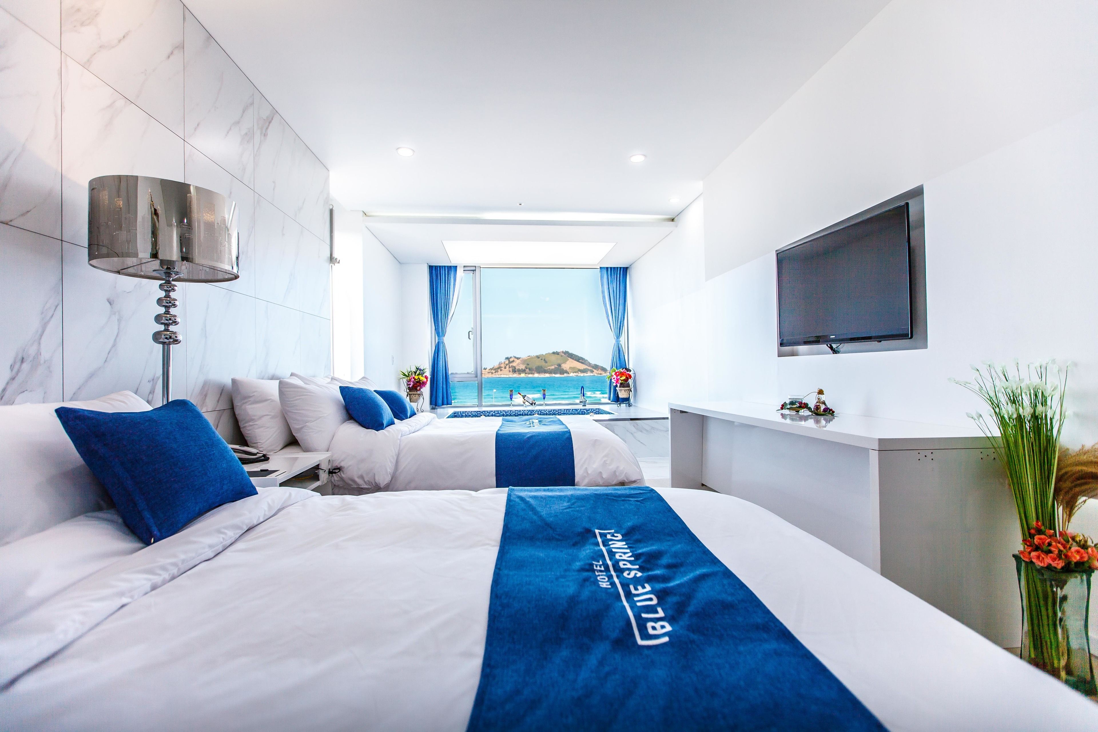 Una moderna camera d'albergo con un letto grande, una scrivania, una TV e vista mare.