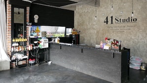Uma área de recepção com balcão, ventilador de teto e parede com o nome "41 Studio" e um slogan.